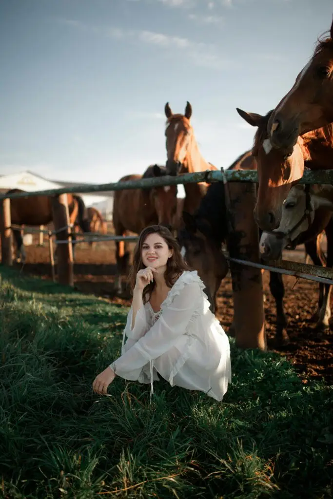 Woman in a white dress squatting by horses on a rural ranch, Texas City. At farm and ranch properties